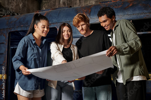 Fotografie group of happy young multicultural friends solving quest task while looking at m