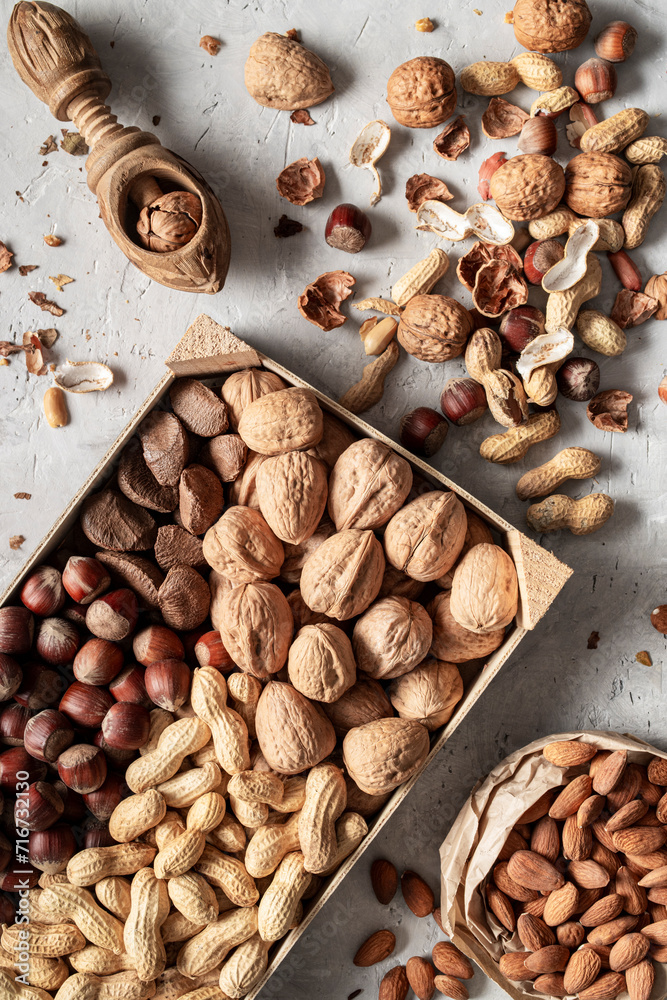 Group of walnuts, hazelnuts, peanuts and blanched almonds, on gray cement surface. Top view. Group of walnuts, hazelnuts, peanuts and blanched almonds, on gray cement surface. Top view.