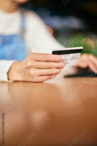 Close-up of a female hand holding a credit card, reading informations.