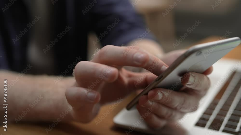 Close up male hands using smartphone at laptop Close up male hands using smartphone at laptop