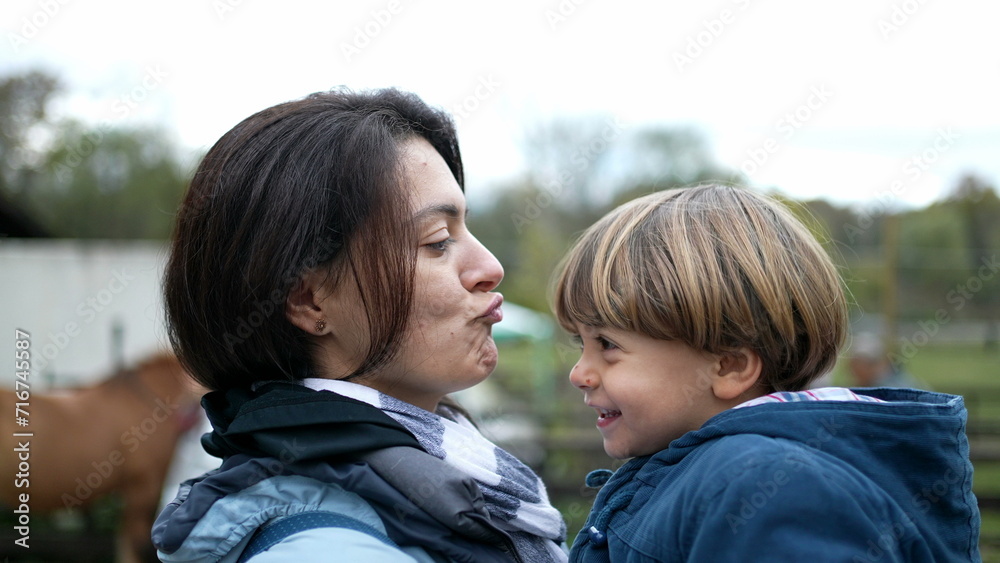 Mother and child bonding outside in authentic real life affectionate moment kissing on the lips and dancing side to side. Mom holding son in arms during fall season Mother and child bonding outside in authentic real life affectionate moment kissing on the lips and dancing side to side. Mom holding son in arms during fall season