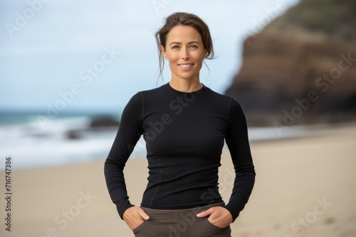 Portrait of a satisfied woman in her 30s showing off a thermal merino wool top against a sandy beach background. AI Generation