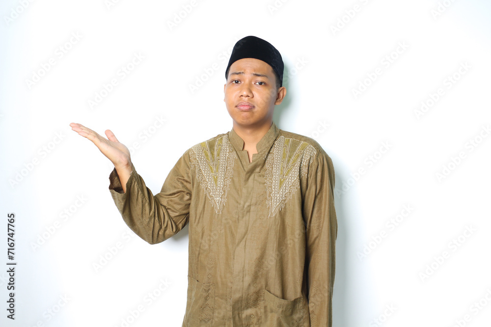 asian muslim man presenting to beside with stressed expression isolated on white background asian muslim man presenting to beside with stressed expression isolated on white background