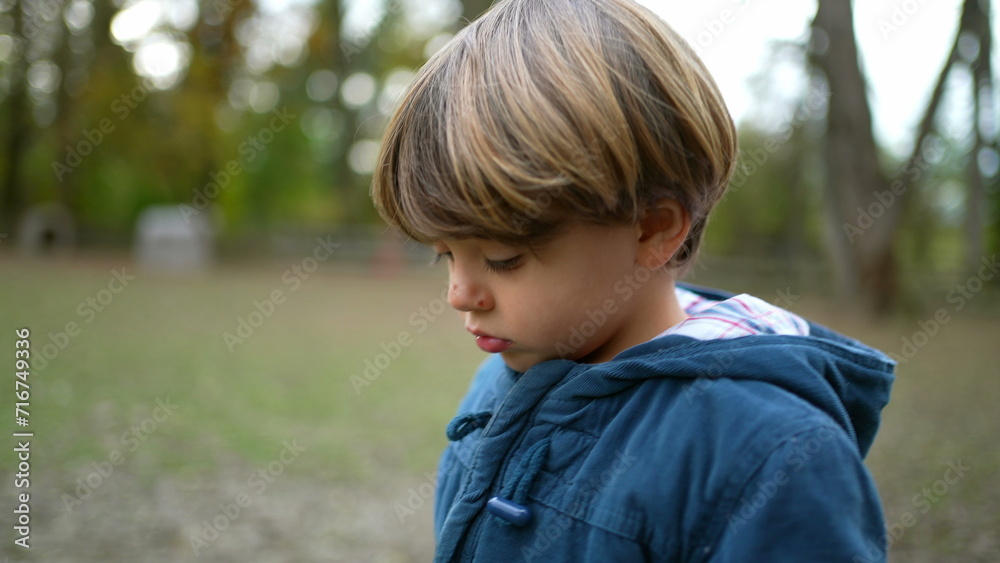 Pensive thoughtful little boy walking outside in nature daydreaming. 4 year old introspective Child walks forward at forest park Pensive thoughtful little boy walking outside in nature daydreaming. 4 year old introspective Child walks forward at forest park