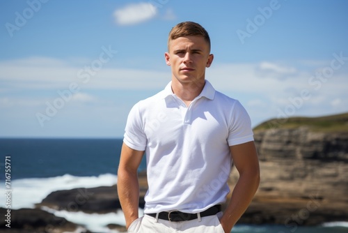 Portrait of a content man in his 20s wearing a breathable golf polo against a rocky shoreline background. AI Generation