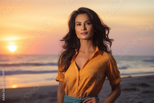 Portrait of a glad indian woman in her 30s dressed in a casual t-shirt against a vibrant beach sunset background. AI Generation