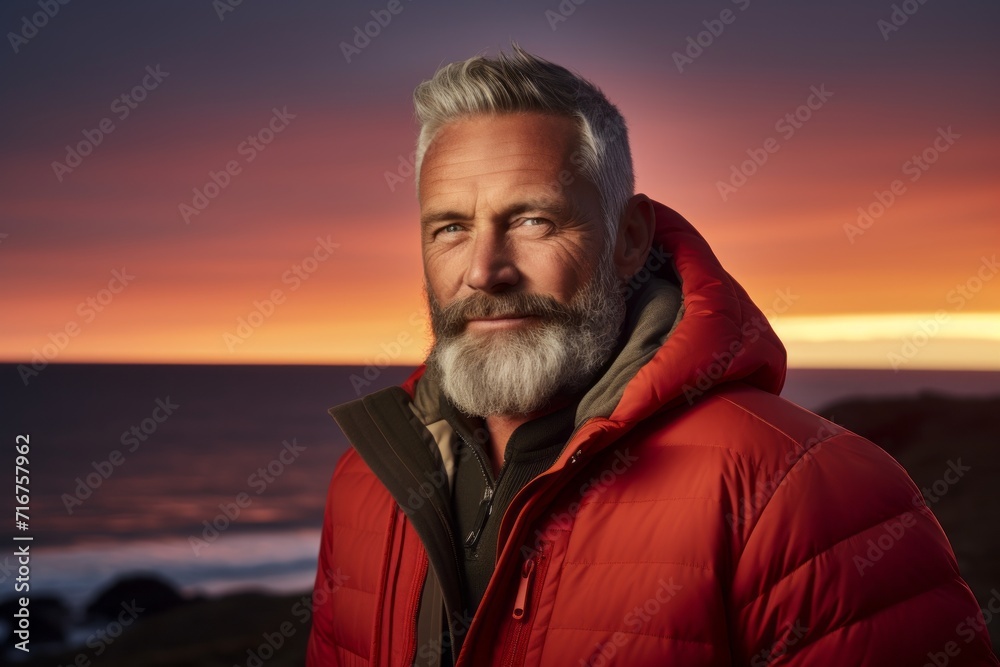 Portrait of a grinning man in his 60s sporting a quilted insulated jacket against a vibrant beach sunset background. AI Generation Portrait of a grinning man in his 60s sporting a quilted insulated jacket against a vibrant beach sunset background. AI Generation