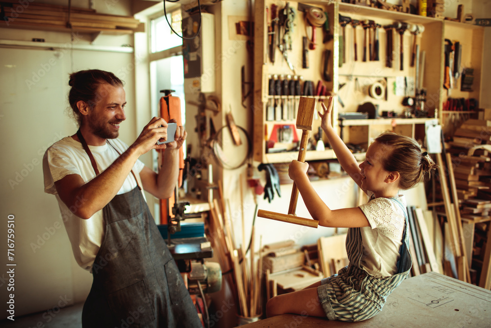 Father teaching daughter woodworking in workshop - obrazy, fototapety, plakaty 