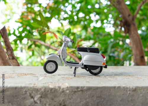 Miniature classic scooter on the cement floor with nature background. After some edits. photo