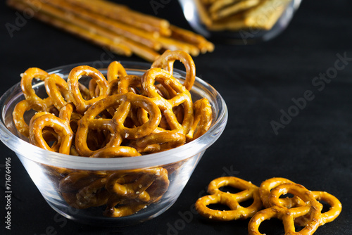 mini pretzels in a glass bowl on a black background. Salty snacks. copy space