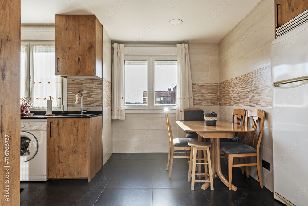 Fototapeta premium A kitchen with chestnut wood cabinets, black synthetic stone countertops, integrated appliances