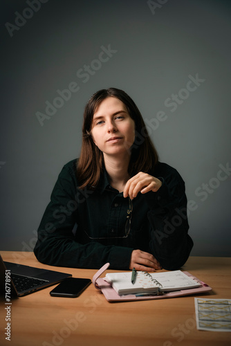 Young and confident business woman holding glasses in her hand at the table