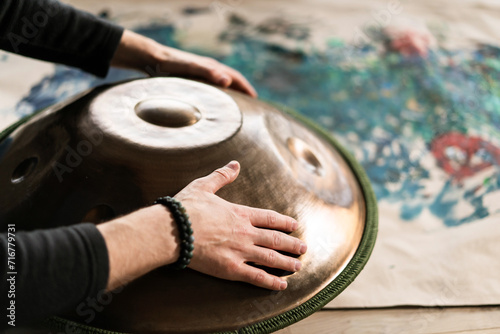 A musician's hand playing the handpan with other people. 