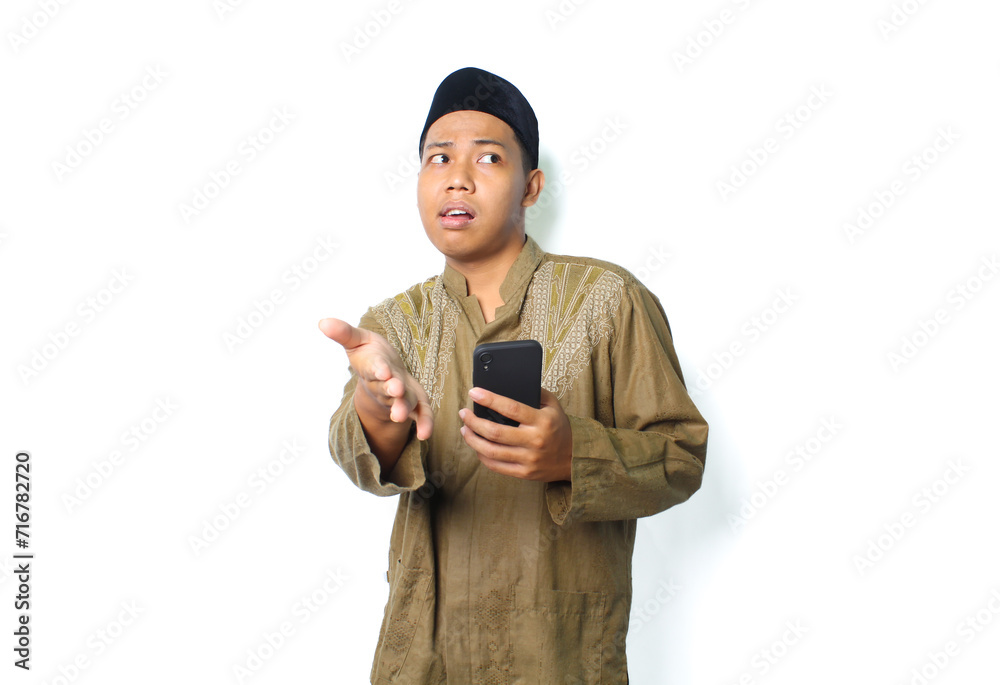 confused asian muslim man holding mobile phone offering handshake isolated on white background confused asian muslim man holding mobile phone offering handshake isolated on white background