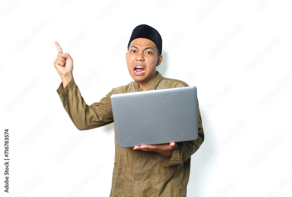 emotional asian muslim man presenting to above with holding laptop wearing islamic clothes isolated on white background