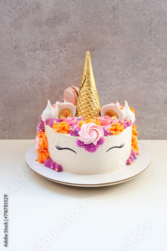 Bright and colorful unicorn cake with beautiful cupcakes decorated with cream cheese frosting, meringue and sprinkles