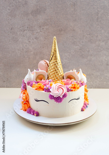 Bright and colorful unicorn cake with beautiful cupcakes decorated with cream cheese frosting, meringue and sprinkles