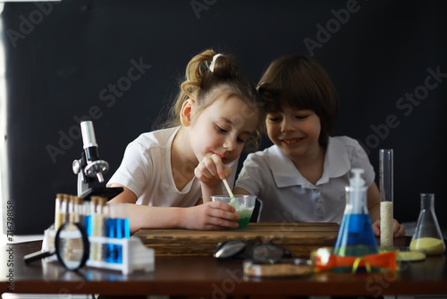 Children scientists. Schoolchildren in the laboratory conduct experiments. Boy and girl experiments with a microscope.