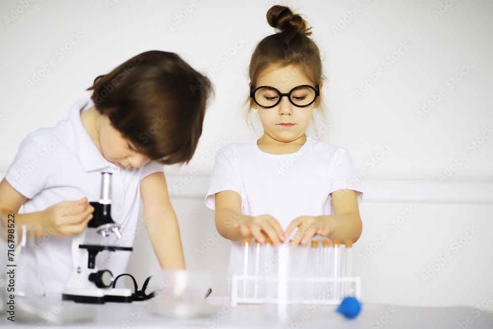 Two cute children at chemistry lesson making experiments on white background Two cute children at chemistry lesson making experiments on white background