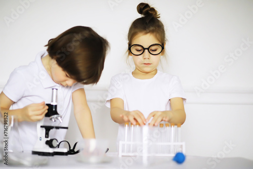 Two cute children at chemistry lesson making experiments on white background