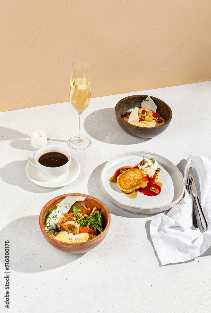 Breakfast spread with omelet, porridge, pancakes accompanied by coffee and sparkling wine