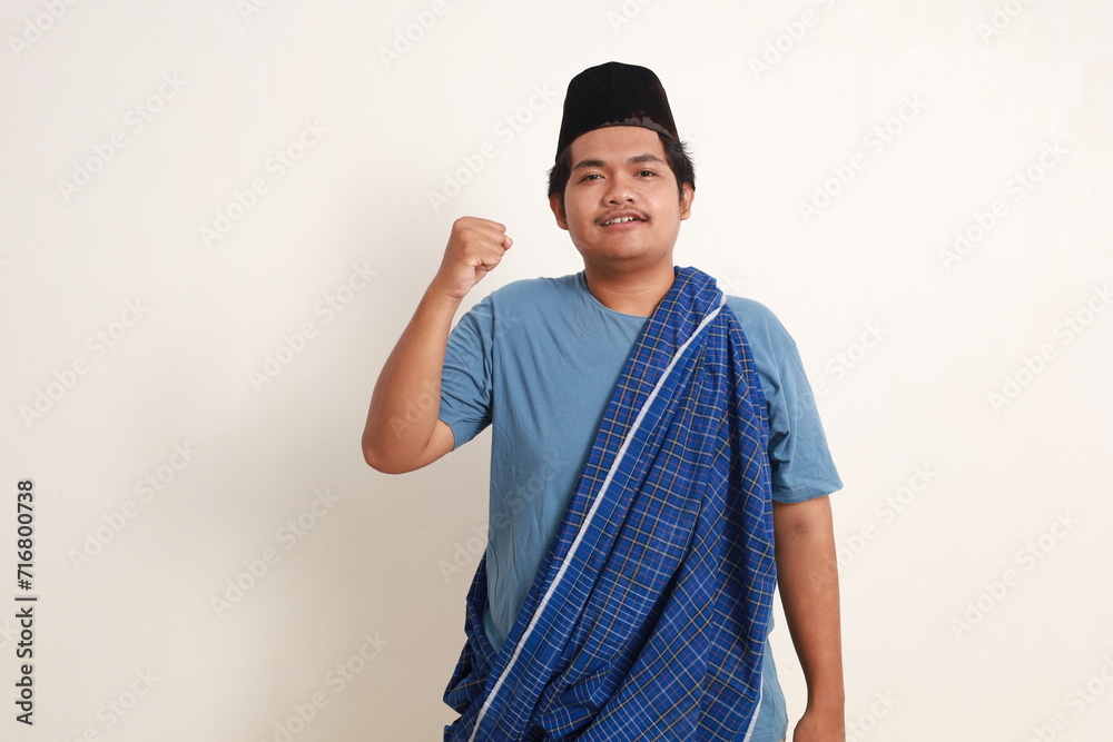 Portrait of a young Asian muslim boy raising his fist with a happy smile on his face as a gesture of celebration Portrait of a young Asian muslim boy raising his fist with a happy smile on his face as a gesture of celebration