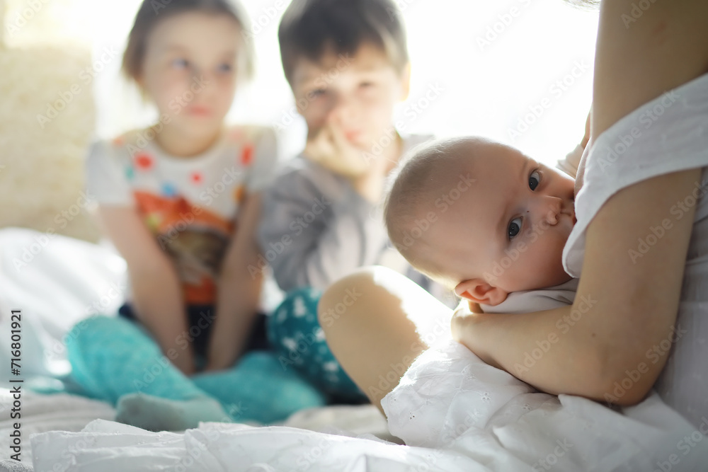 Maternity concept. A young mother feeds her little baby. First lure and breastfeeding. Family in white clothes. Maternity concept. A young mother feeds her little baby. First lure and breastfeeding. Family in white clothes.