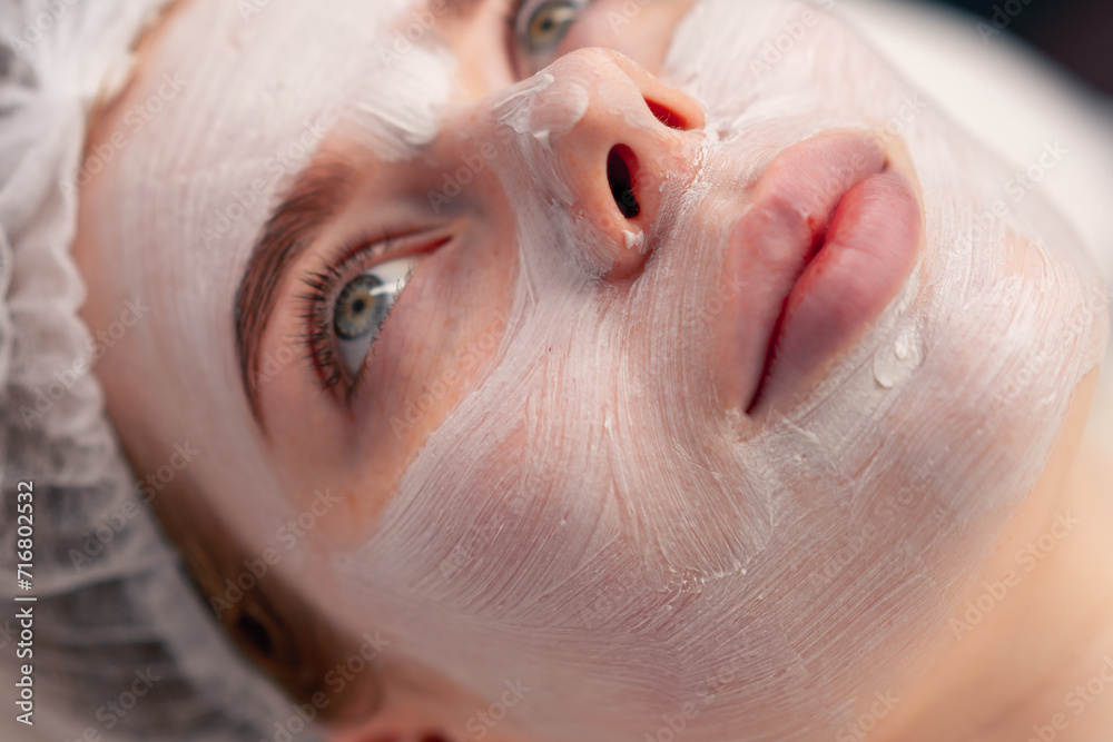 Naklejka premium close-up of a girl's face with a cream or mask during a cosmetic procedure in a beauty salon