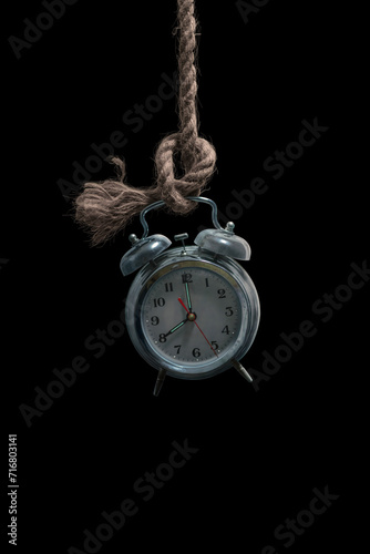 An old classic antique clock hanged with a rope, a mysterious close up of analog round clock hanging in a dark place isolated on black background, cinematic horror style, retro type countdown image. 