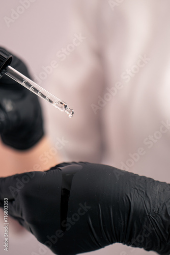 close-up beautician squeezes facial serum from a pipette during a cosmetic procedure in beauty salon