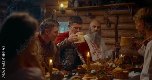 gathering of medieval Slavic village dwellers, men in historical suits dinning, 4K, Prores photo