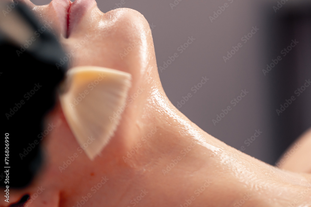 Naklejka premium close-up beautician in gloves applies a mask on the face of a client with a brush care for the skin