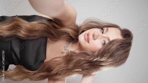An elegantly dressed girl with evening makeup, hairstyle and jewelry makes a vertical video on her phone's selfie camera. A young woman take a selfie with the front camera of her smartphone.