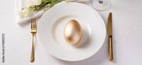 golden easter egg on a white plate, gold cutlery
