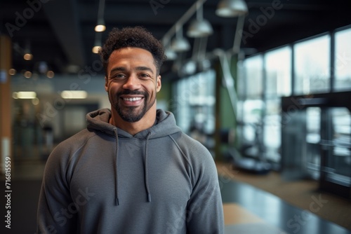Portrait of a tender afro-american man in his 30s dressed in a comfy fleece pullover against a dynamic fitness gym background. AI Generation