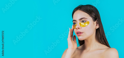 Portrait of beauty woman with eye patches showing an effect of perfect skin. Eyes mask cosmetic patches woman face closeup. Woman applying golden eye patches. Close up portrait girl photo