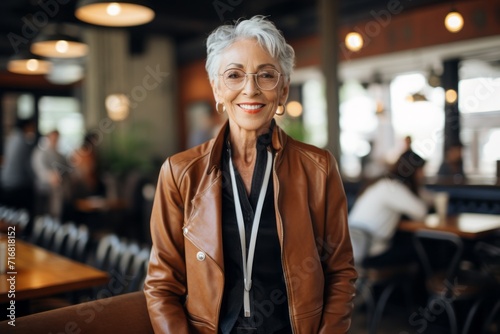 Portrait of a happy woman in her 70s sporting a stylish leather blazer against a serene coffee shop background. AI Generation