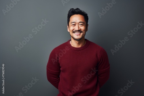 Portrait of a cheerful asian man in his 30s dressed in a warm wool sweater against a minimalist or empty room background. AI Generation