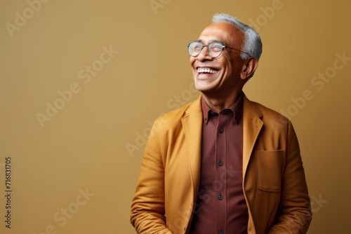 Portrait of a happy indian man in his 70s dressed in a stylish blazer against a minimalist or empty room background. AI Generation