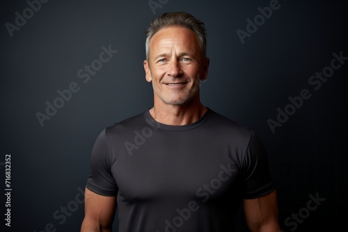 Portrait of a satisfied man in his 60s wearing a moisture-wicking running shirt against a minimalist or empty room background. AI Generation