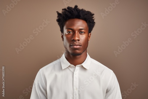 Portrait of a tender afro-american man in his 20s wearing a simple cotton shirt against a minimalist or empty room background. AI Generation © CogniLens