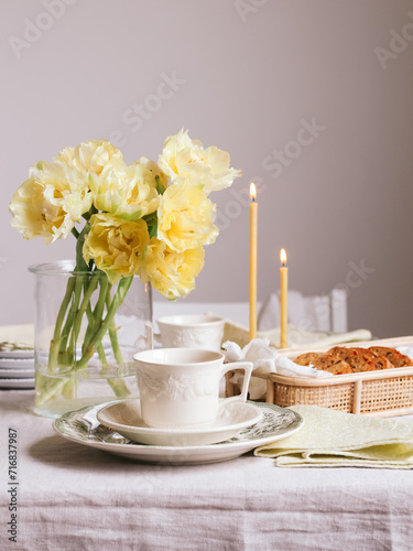 Breakfast table for two with yellow tulips and candles