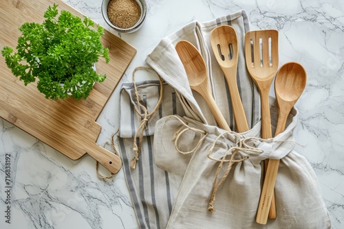 Stylish eco-friendly kitchenware set with wooden utensils, bamboo cutting board, and fresh parsley on a marble countertop. photo