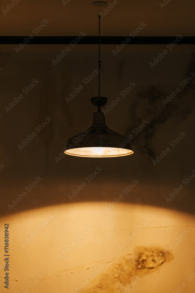 a hanging lamp with a light bulb in the room. metal lampshade at the chandelier in the room