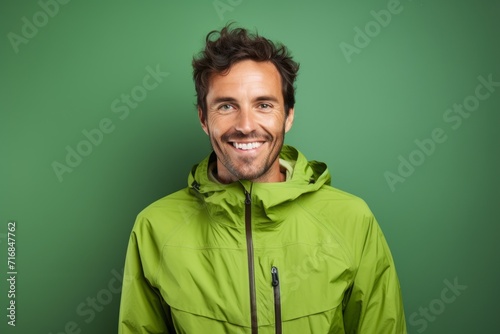 Portrait of a smiling man in his 30s wearing a windproof softshell against a solid pastel color wall. AI Generation