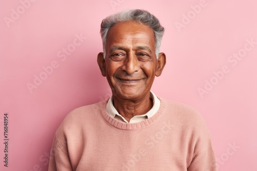 Portrait of a happy indian man in his 80s showing off a thermal merino wool top against a solid pastel color wall. AI Generation