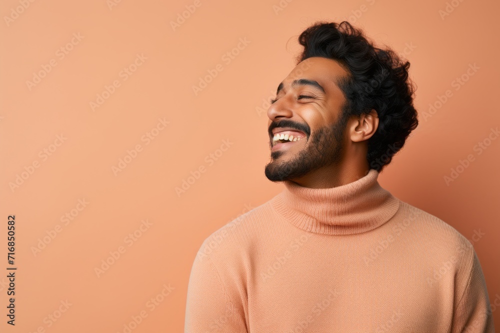 Portrait of a joyful indian man in his 20s wearing a classic turtleneck sweater against a solid pastel color wall. AI Generation