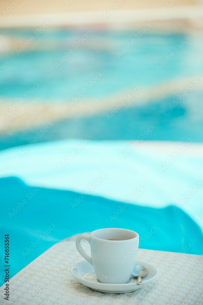 a cup of coffee by the pool with emerald water on a sunny day. rest at the pool.