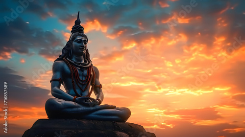 back lit statue of hindu god lord shiva in meditation posture with dramatic sky from unique angle,