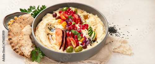 Hummus. Large bowl of homemade hummus garnished with chickpeas, vegetables and olive oil. Middle east food.